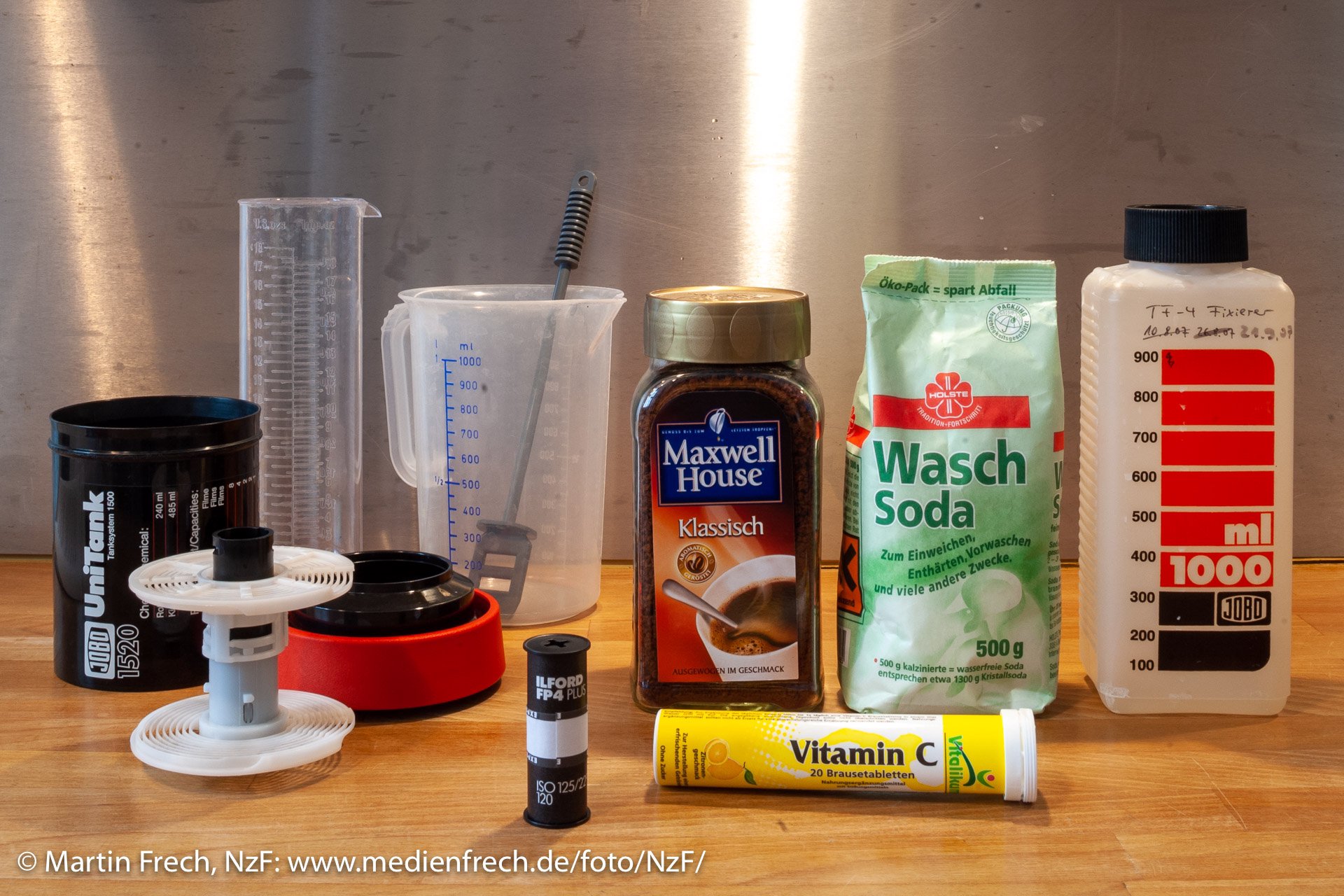 Zubehör für die Filmentwicklung mit Kaffee (Caffenol) (Foto: Martin Frech, 9/2007) Stilleben mit Entwicklungsdose, Meßbecher, Mensur, einem Glas mit Instant-Kaffeepulver, einem Beutel Waschsoda und einer Rolle Vitamin-C-Tabeletten sowie einem belichteten Rollfilm (Farbbild) (Foto: Martin Frech, 9/2007)